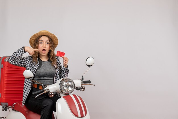 Mulher jovem em ciclomotor apontando para o cartão de frente