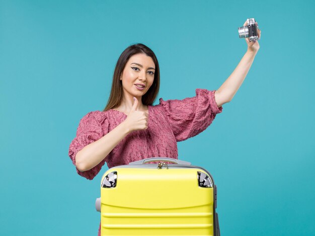 Mulher jovem em férias tirando foto com a câmera no fundo azul Viagem mulher no exterior