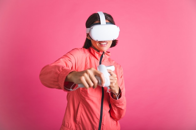 Mulher jovem em forma de esporte usa paletó e óculos de realidade virtual, jogando boxe, luta, rosa