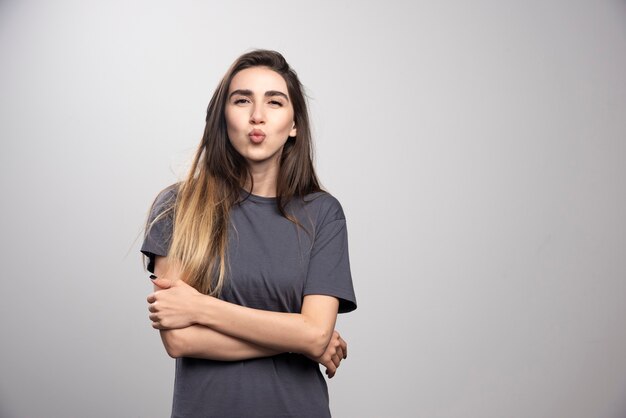 Mulher jovem em pé e posando com os braços cruzados