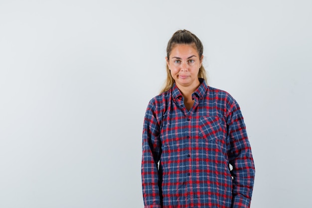 Mulher jovem em pé e posando na frente com uma camisa quadriculada e bonita