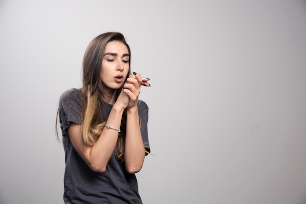 Mulher jovem em pé e posando sobre um fundo cinza