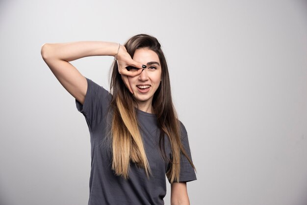 Mulher jovem em pé e posando sobre um fundo cinza