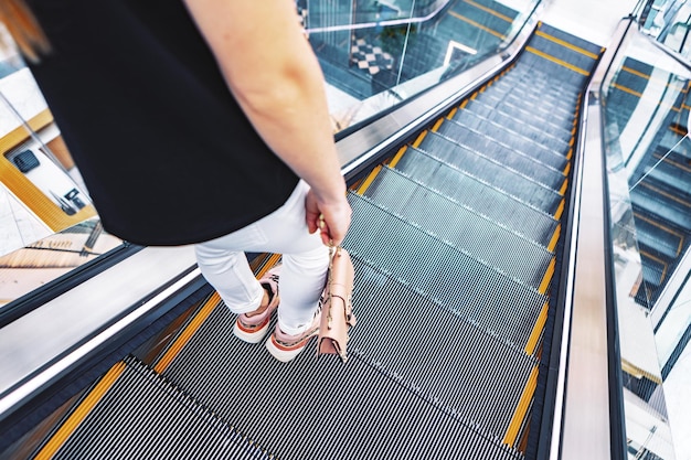 Mulher jovem em pé na escada rolante do metrô