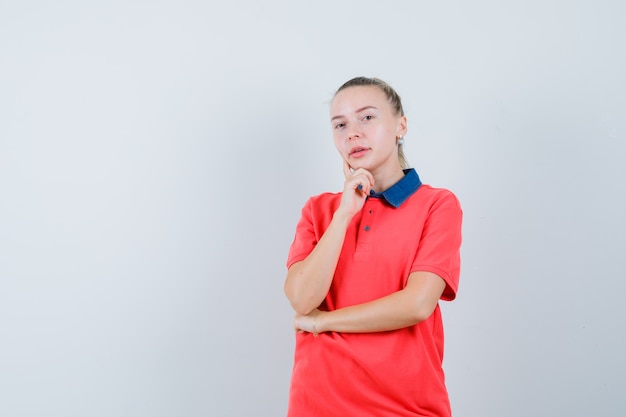 Mulher jovem em pose pensativa com uma camiseta e aparência sensata