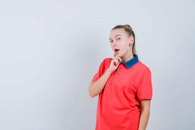 Mulher jovem em pose pensativa com uma t-shirt parecendo surpresa