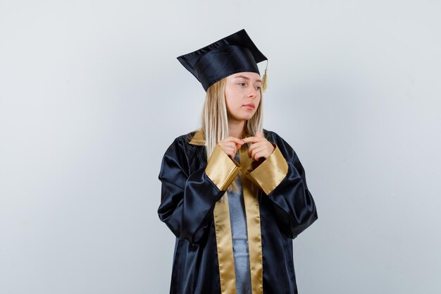 Mulher jovem em pose pensativa com uniforme de pós-graduação e parecendo triste