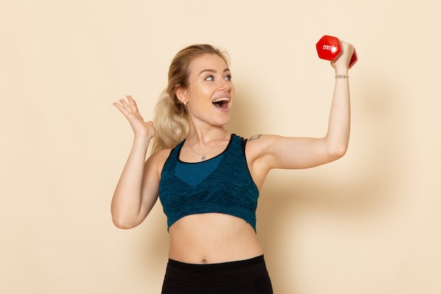 Mulher jovem em roupa esportiva segurando halteres de frente