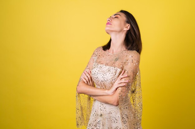 Mulher jovem em um vestido bege cintilante de noite de véspera de ano novo celebra as festas de fim de ano