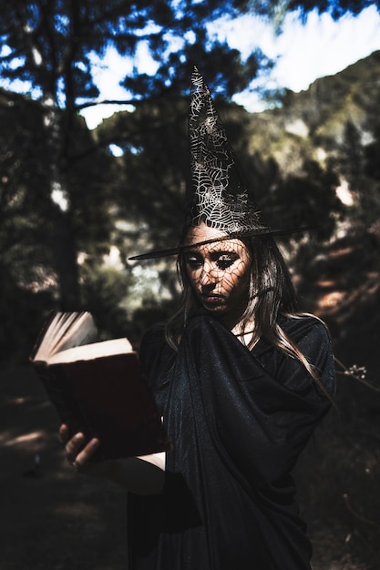 Mulher jovem, em, wizard, traje, livro leitura, em, floresta