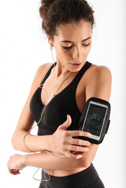 mulher jovem encaracolado morena fitness ouvindo música e usando o smartphone