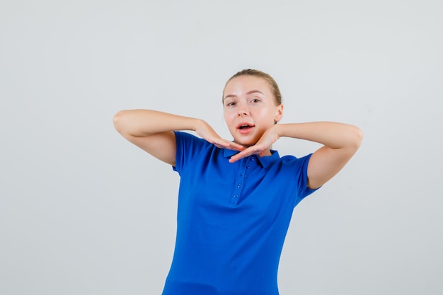 Mulher jovem esticando os cotovelos em uma camiseta azul e parecendo alegre