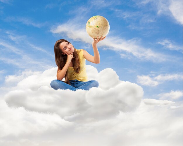 Mulher jovem estudante olhando-o globo do mundo sentado em uma nuvem