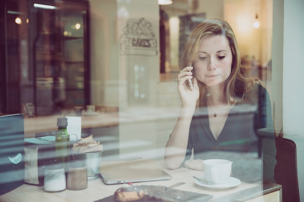 Foto grátis mulher jovem, falando telefone, em, cozy, café