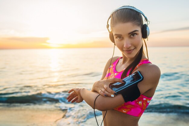 Mulher jovem fazendo exercícios esportivos na praia ao nascer do sol pela manhã