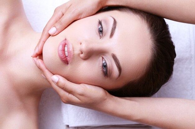 Mulher jovem fazendo massagem facial