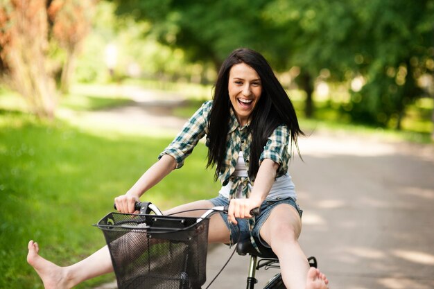 Mulher jovem feliz andando de bicicleta pelo parque