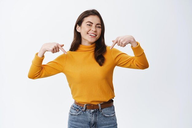 Mulher jovem feliz apontando o dedo para o logotipo e rindo despreocupada em branco