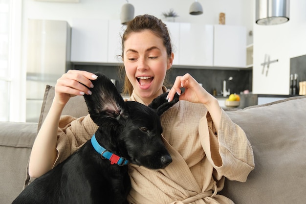 Foto grátis mulher jovem feliz brincando com seu animal de estimação, rindo e sorrindo, aproveitando o tempo com sua adorável