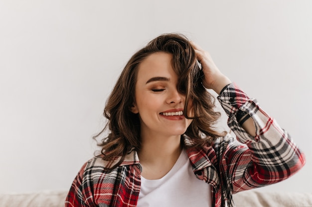 Foto grátis mulher jovem feliz com camisa xadrez sorri e brinca com o cabelo