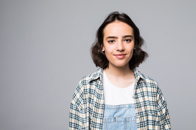 Mulher jovem feliz com os braços cruzados pela parede cinza, olhando.