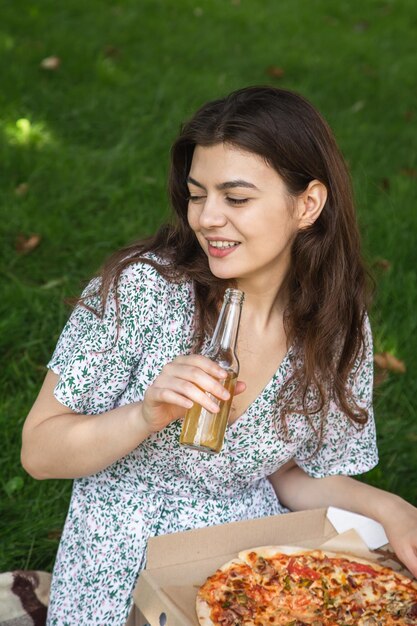 Mulher jovem feliz comendo pizza em um piquenique