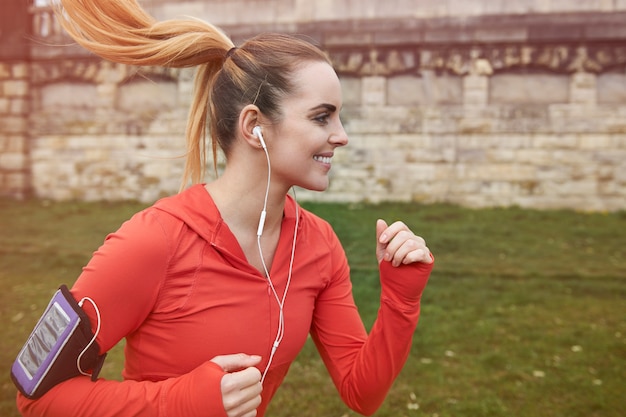 Mulher jovem feliz correndo ao ar livre. Ela está se preparando para a maratona