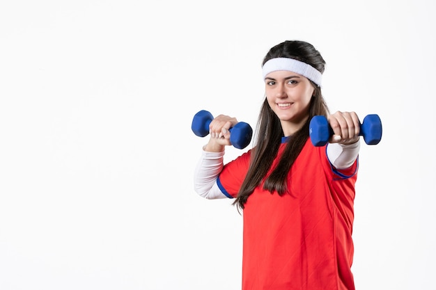 Mulher jovem feliz de vista frontal com roupas esportivas e halteres azuis