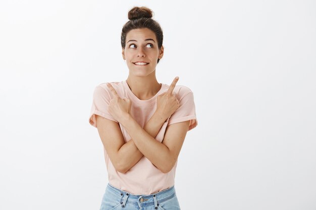 Mulher jovem feliz e elegante posando contra a parede branca