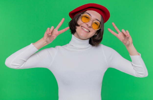 Foto grátis mulher jovem feliz e positiva com cabelo curto em gola alta e boina