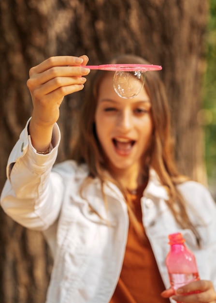 Foto grátis mulher jovem feliz fazendo bolhas de sabão