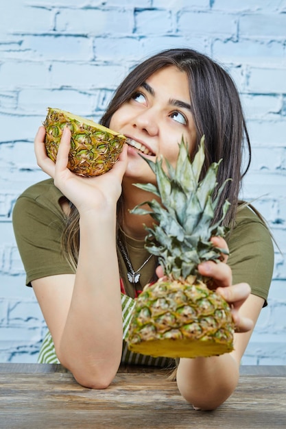 Foto grátis mulher jovem feliz segurando duas metades de abacaxi.