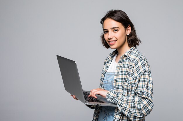 Mulher jovem feliz segurando laptop e olhando