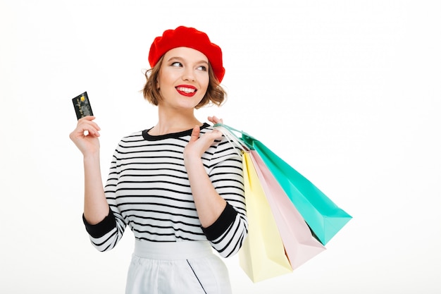 Mulher jovem feliz, segurando o cartão de crédito e sacolas de compras