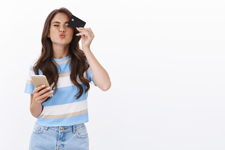 Foto grátis mulher jovem, fofa e adorável, gosta de fazer compras online, fazer beicinho, mandar beijo, segurar cartão de crédito show de smartphone