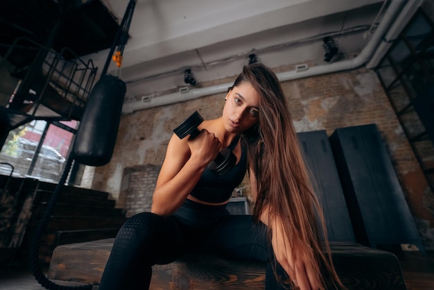 Mulher jovem fortalece os músculos com um braço levantando halteres
