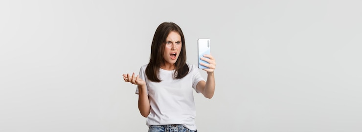 Foto grátis mulher jovem frustrada tendo uma discussão em chamada de vídeo segurando um smartphone de pé com fundo branco