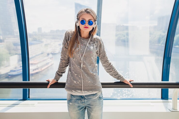 Foto grátis mulher jovem hippie em roupa casual se divertindo ouvindo música em fones de ouvido