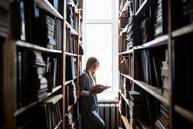 Mulher jovem, leitura, entre, bookcases