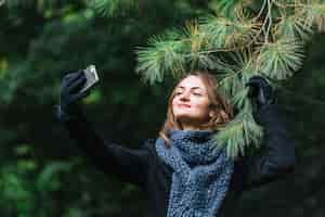 Foto grátis mulher jovem, levando, selfie, ligado, smartphone, perto, coniferous, ramo