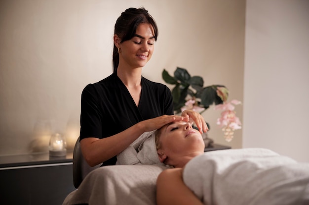 Mulher jovem massageando o rosto do cliente