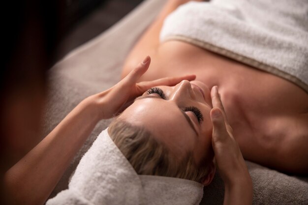 Mulher jovem massageando o rosto do cliente