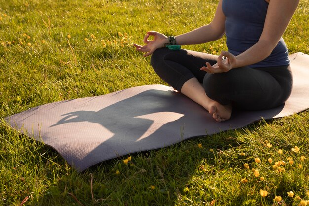 Mulher jovem meditando ao ar livre no tapete de ioga