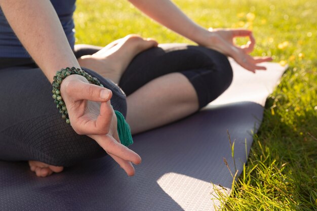 Mulher jovem meditando ao ar livre no tapete de ioga