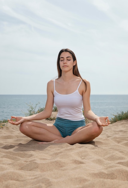 Mulher jovem meditando na areia