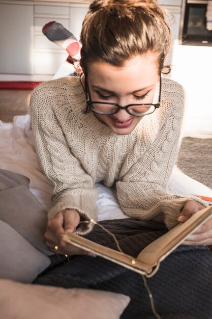 Mulher jovem, mentindo, ligado, cobertor, com, livro, e, sorrindo