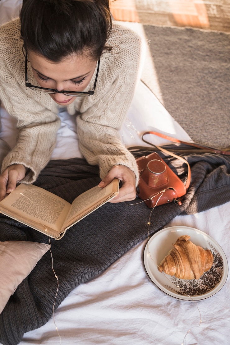 Foto grátis mulher jovem, mentindo, ligado, cobertor, e, livro leitura