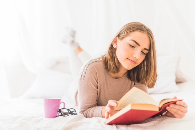 Mulher jovem, mentindo livro leitura cama