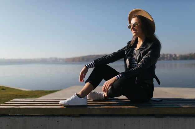 Mulher jovem modelo posando em um dia de outono na orla do lago, vestida com roupas casuais