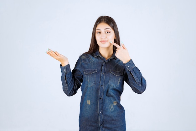 Mulher jovem mostrando algo em sua mão aberta